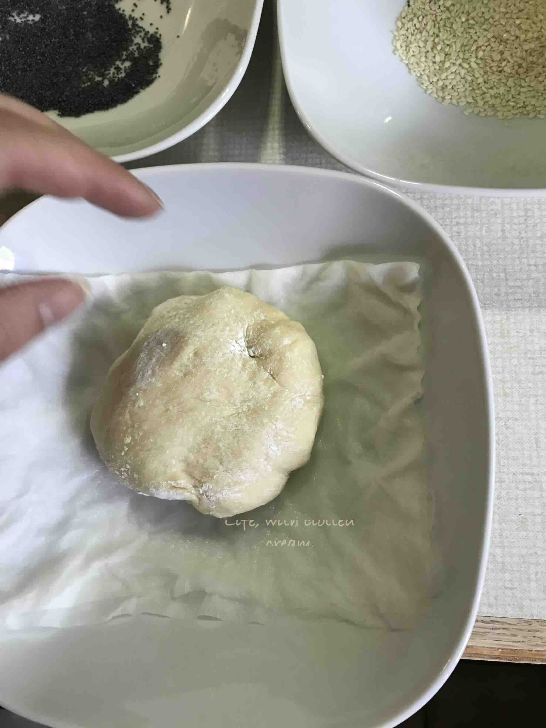 Dipping the proved and shaped kaiser rolls in water using some kitchen roll to allow the poppy seeds to stick.