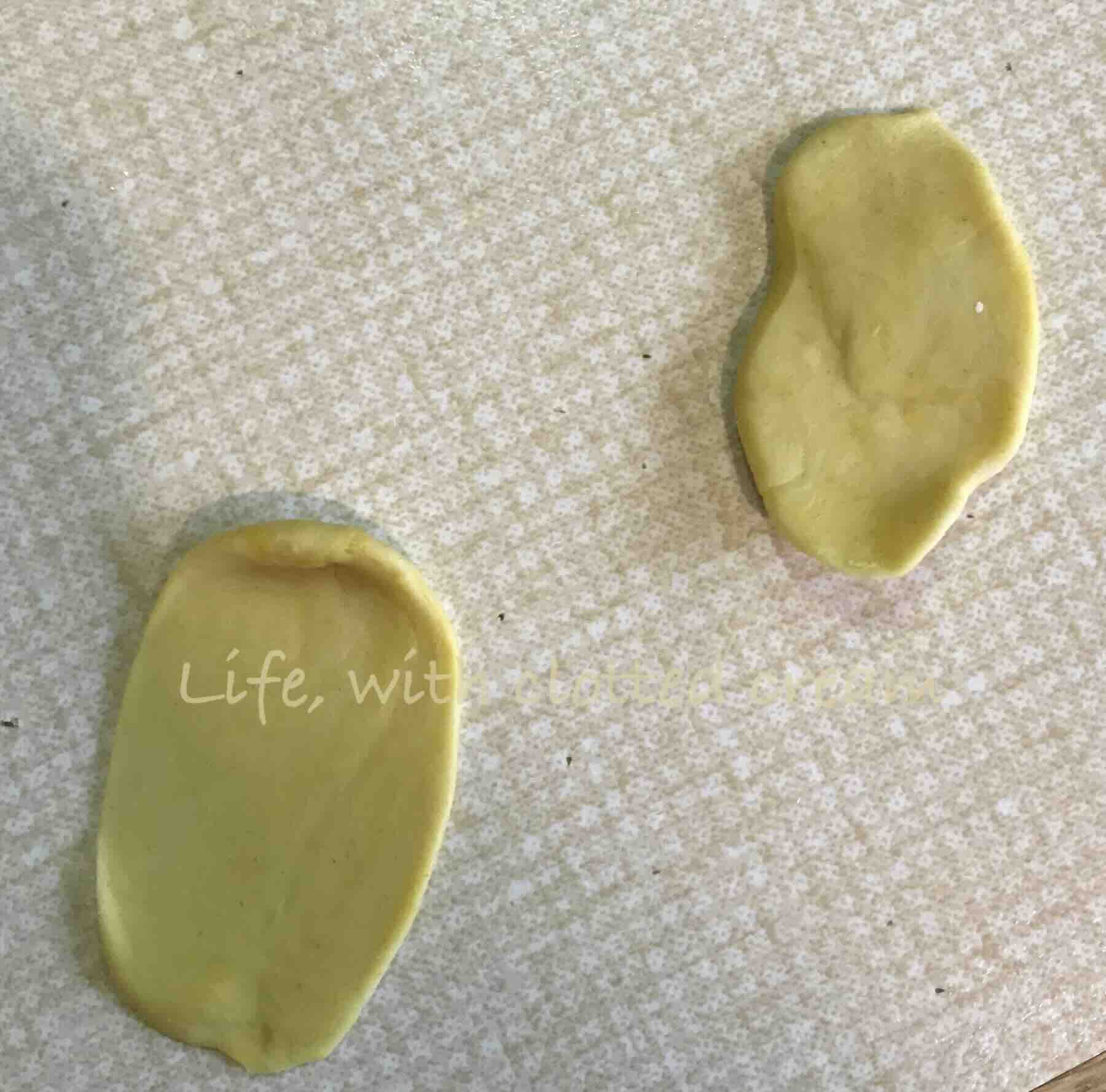 Two pieces of dough in a mustard yellow colour rolled into ovals.