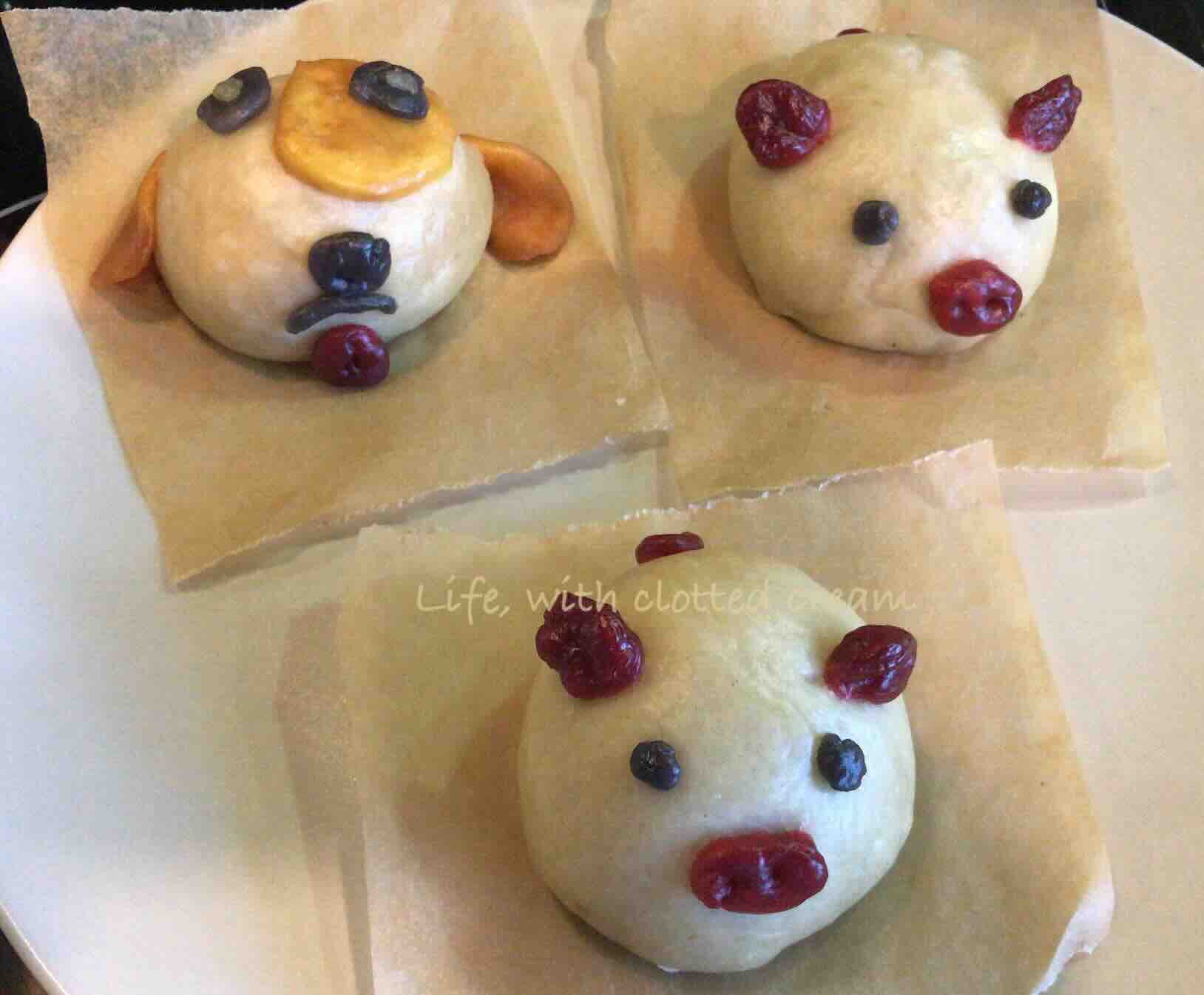 Three custard filled bao in the shape of two piglets and one dog on parchment paper after being steamed.