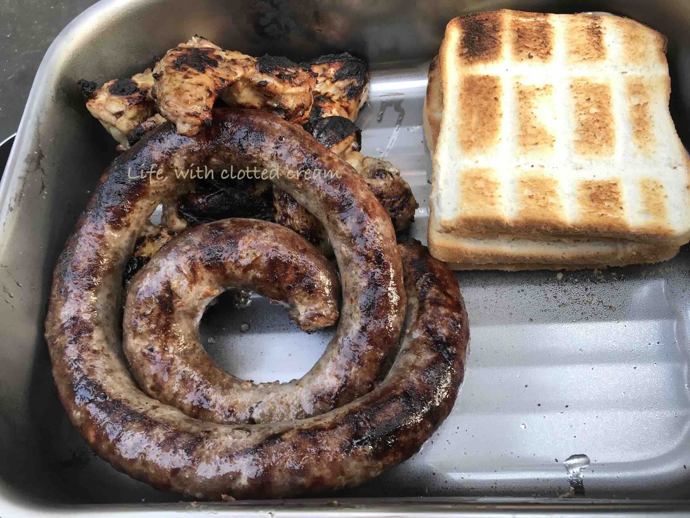 Braaibroodjies with boerewors and chicken wings in a braaibak.