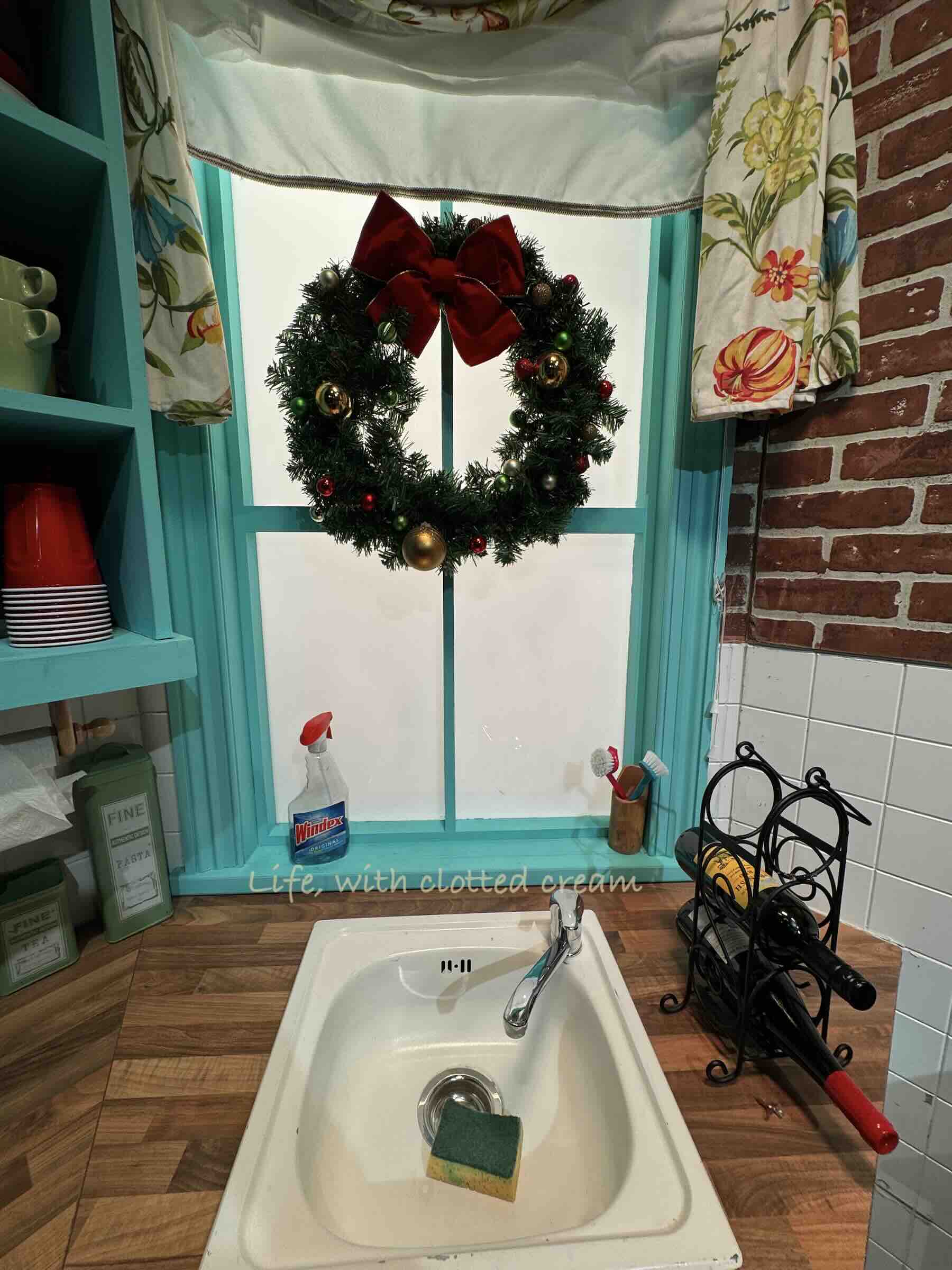 Monica and Rachel's sink with a sponge inside and a Christmas wreath in the window.