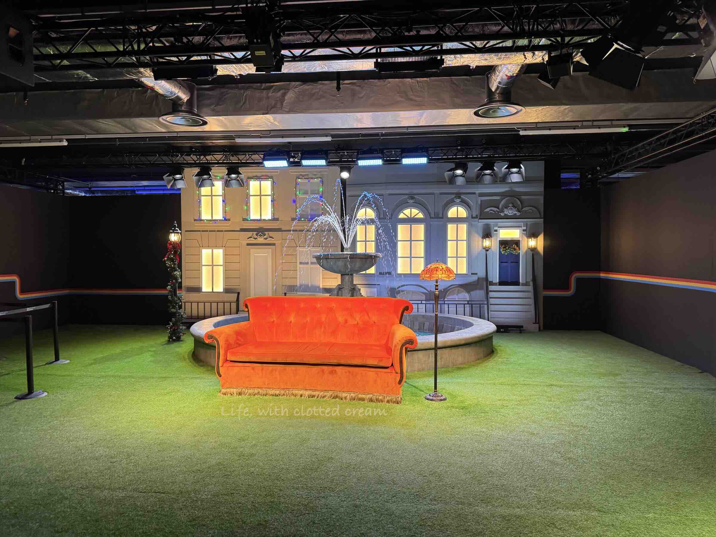 The orange couch from Friends in front of a fountain and a lamp next to it.