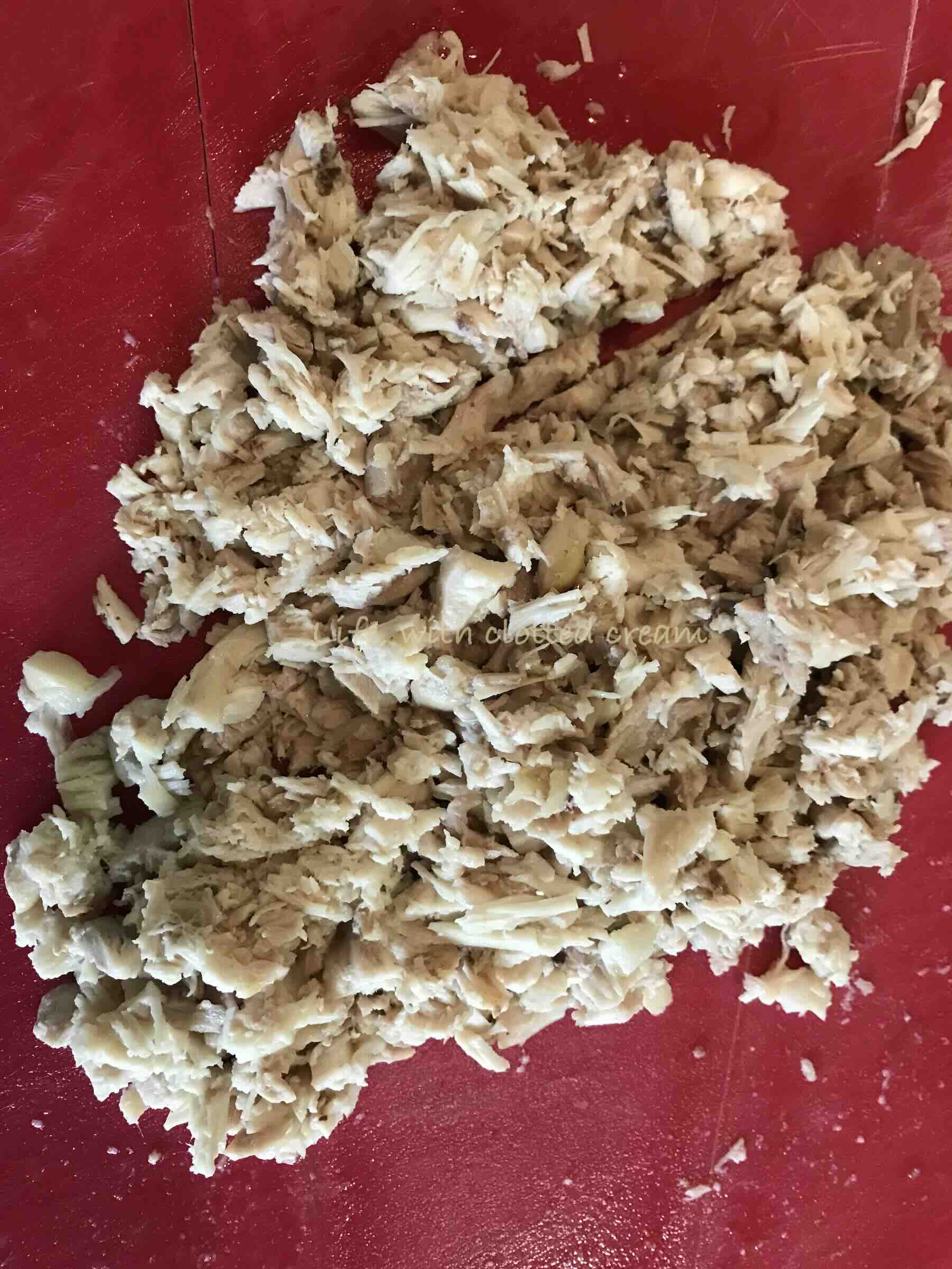 Shredded chicken on a red board.