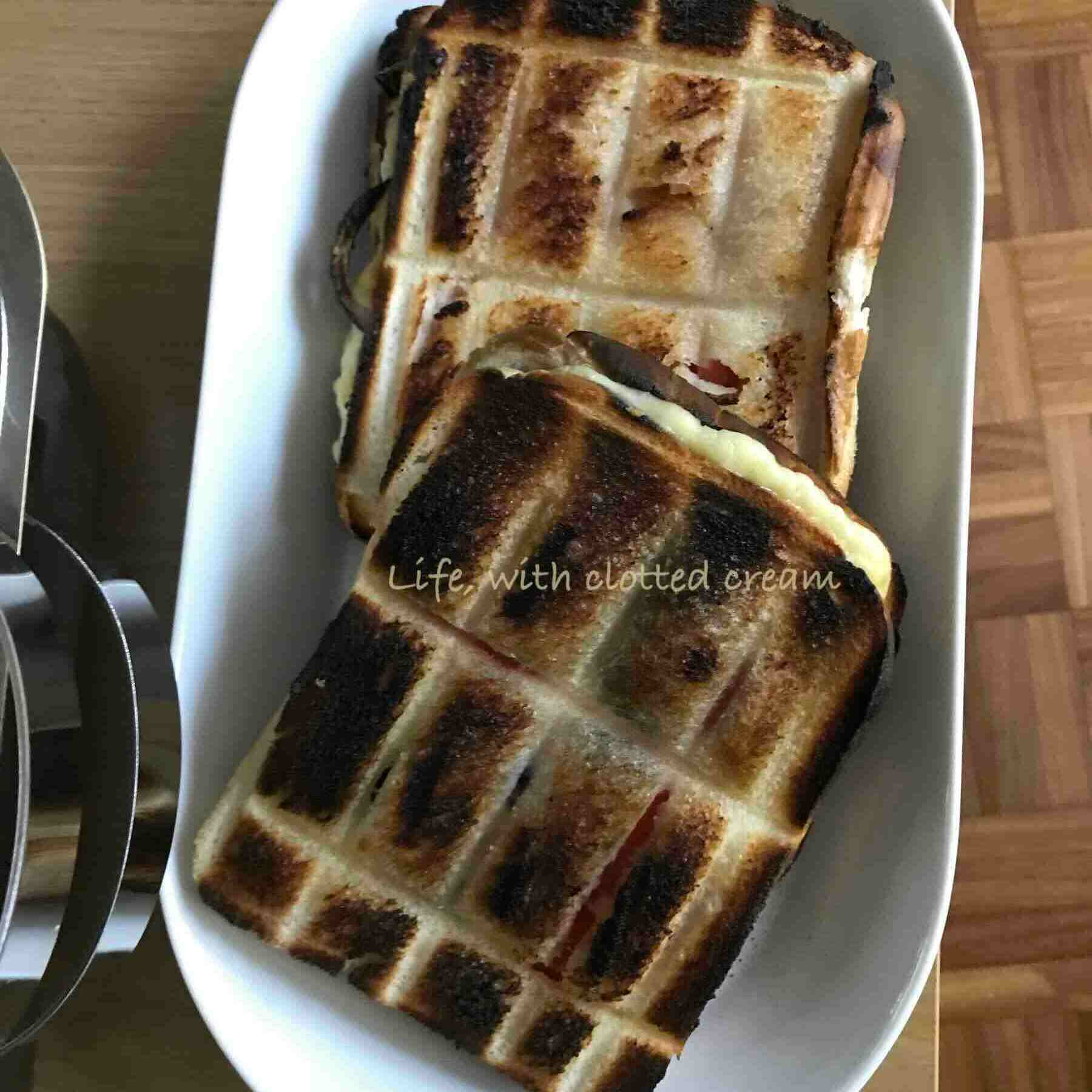 Two braaibroodjies in a white oval plate next to a braaibak.