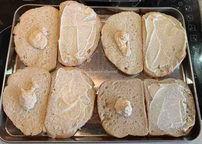 Sliced rustic bread with truffle mayo on one side and garlic mayo on the other.