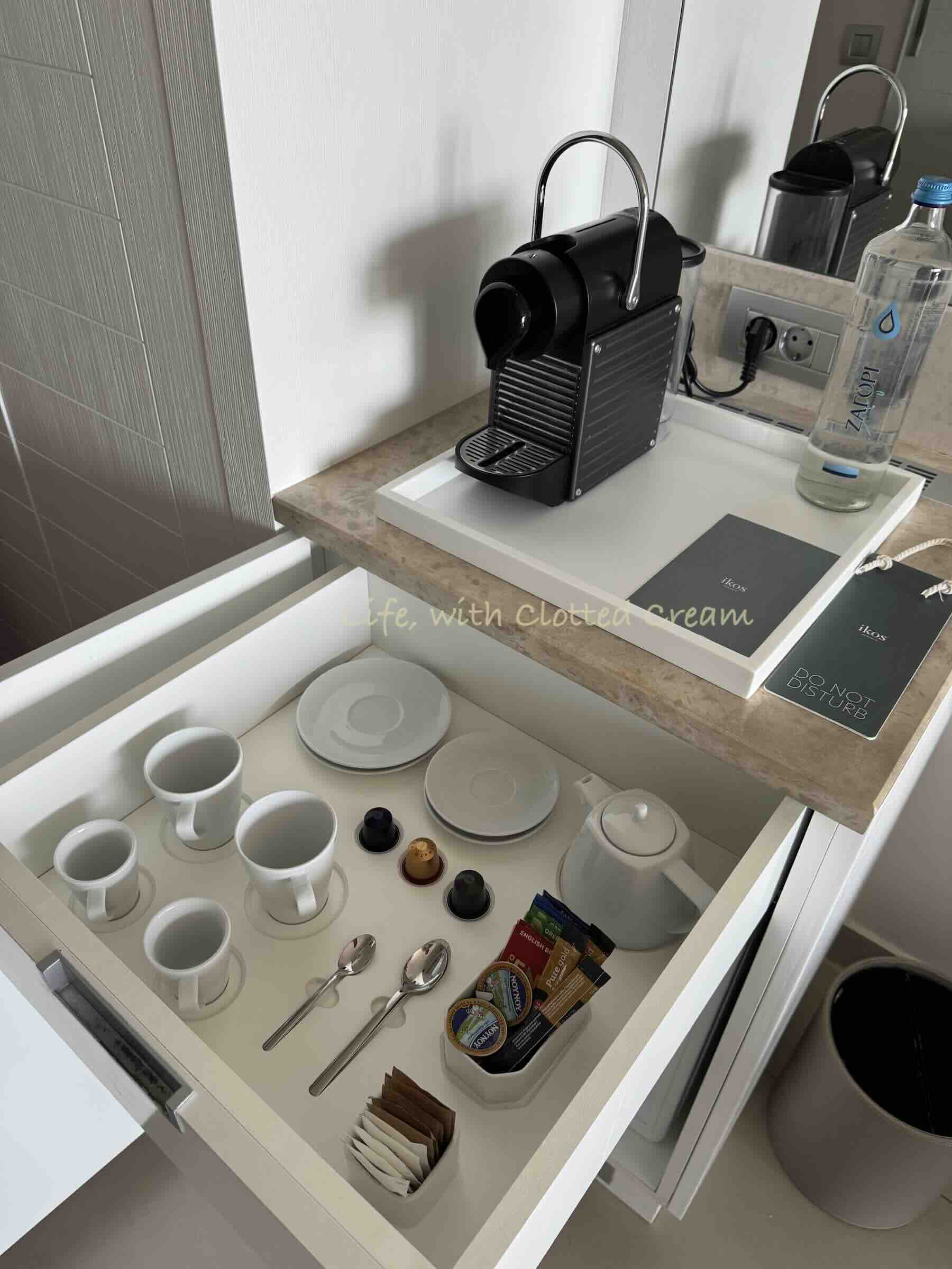 A coffee machine with drawer full of cups and cutlery.
