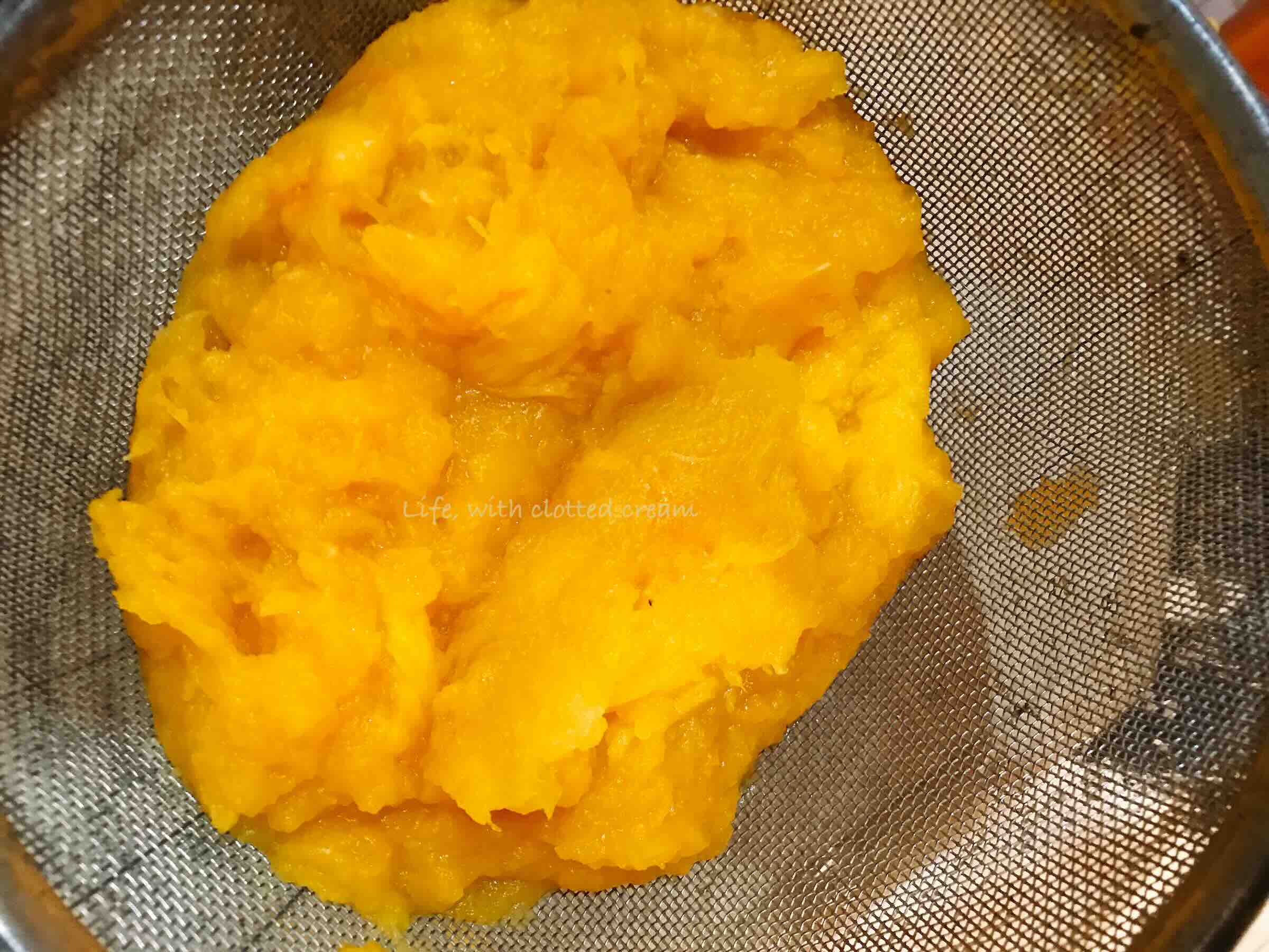 Yellow gem squash flesh in a sieve.