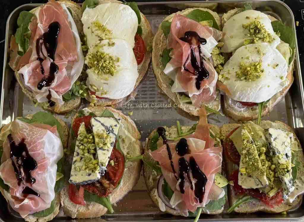 Slices of bread with prosciutto and balsamic glaze on one side and cheese and pistachio on the other.