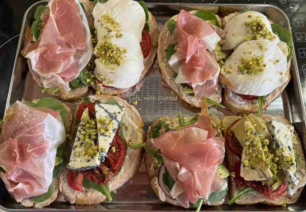Slices of bread with prosciutto on one side and mozzarella and pistachio on the other.