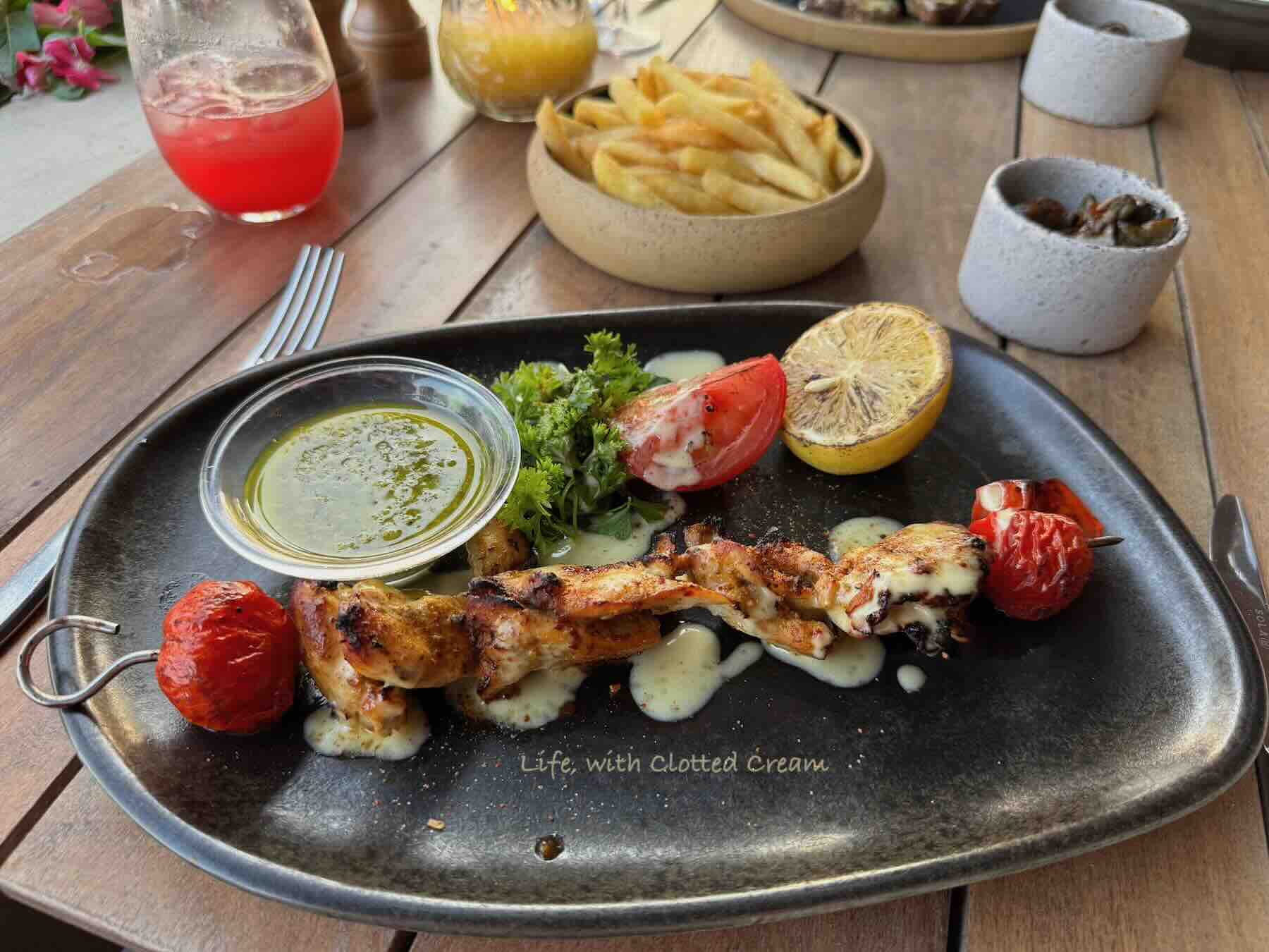 Chicken on a skewer with a salad and dressing on the side.